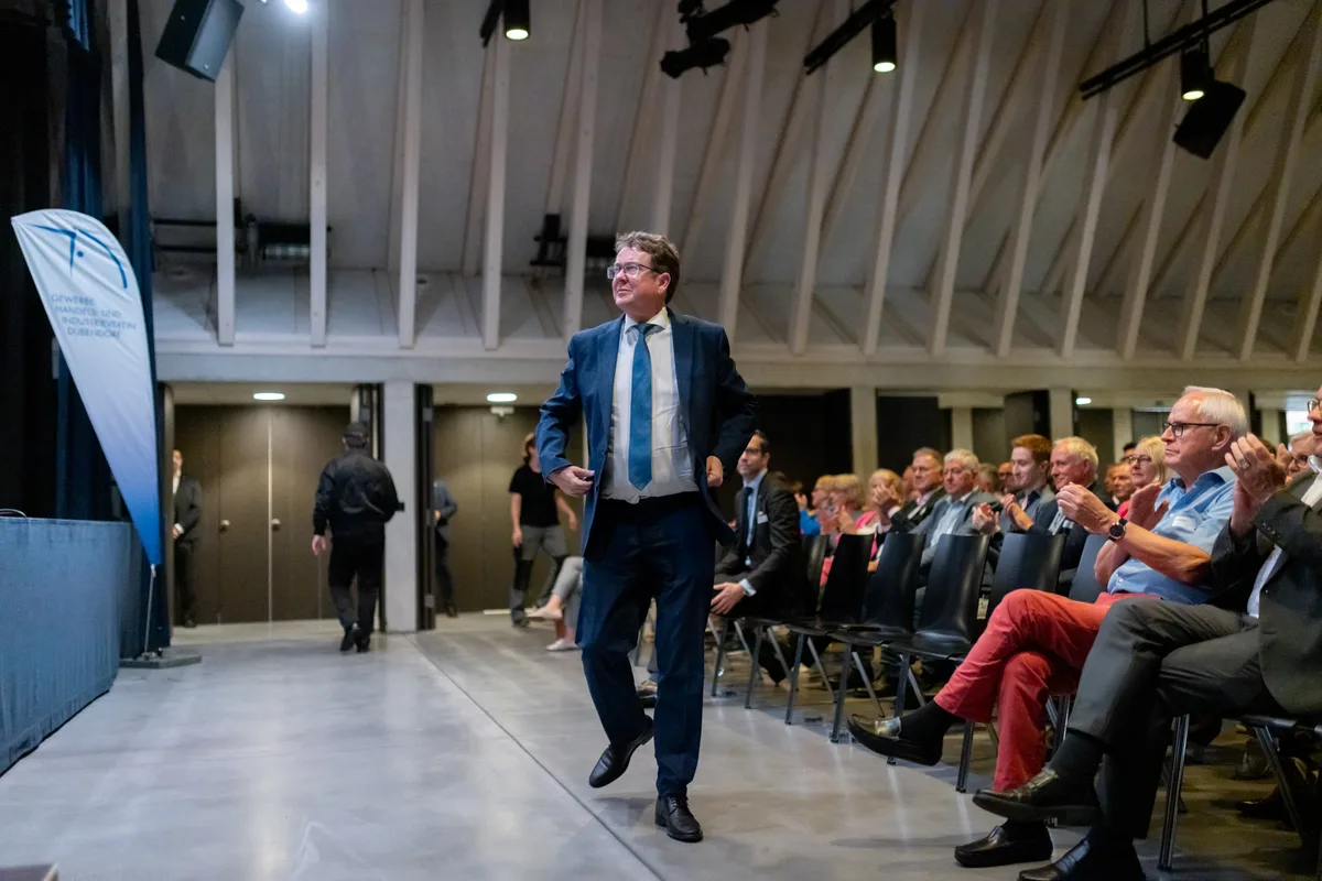 Ein Mann schreitet zur Bühne, das Publikum applaudiert. 
